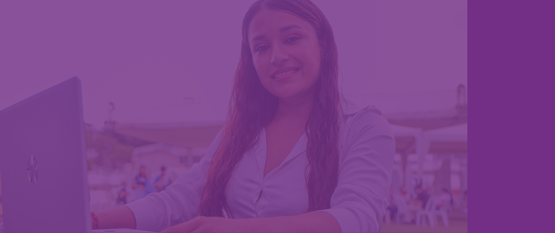 Mujer joven sonriendo frente a una laptop en un evento al aire libre
