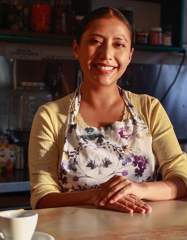 Mujer sonriendo tras el mostrador de su cafetería
