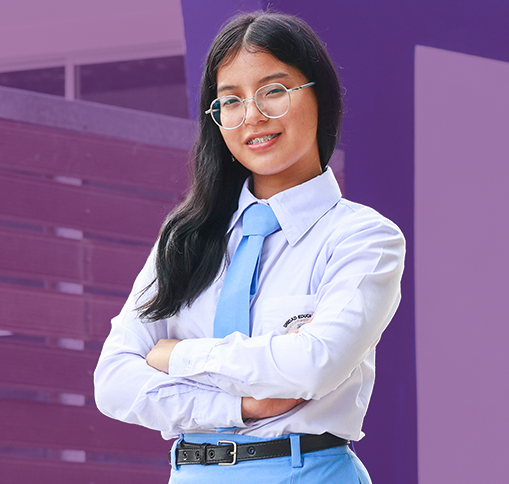 Estudiante con uniforme y gafas, de brazos cruzados frente a su colegio